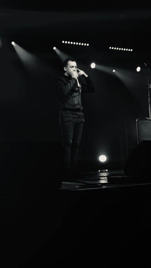 Majid standing on stage with a mic, black and white image.